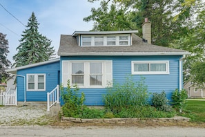 A two-story house with a blue exterior, white trim, and a chimney. There is a small porch with a white railing and a stone wall in front. - Walk to Beach! Luna Pier Haven w/ Yard & Views (Luna Pier)