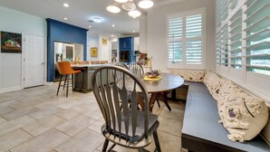 A modern kitchen with a dining area, featuring a built-in oven, a dining table with chairs, and a bench with cushions. - Pool, Patio + Game Room! Secluded Montverde Home (Montverde)
