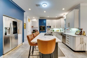 A modern kitchen with a central island, stainless steel appliances, and a blue accent wall.