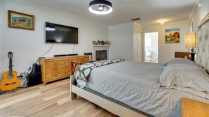 A bedroom with a bed, a television, a guitar, a dresser, and a painting on the wall. - Pool, Patio + Game Room! Secluded Montverde Home (Montverde)