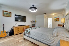 Ein Schlafzimmer mit einem Bett, einem Fernseher, einer Gitarre, einem Schminktisch und einem Bild an der Wand.