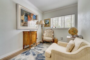 A room with a large framed painting, a lamp, a globe, and a patterned armchair.