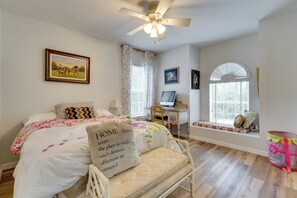 A bedroom with a bed, a desk, a computer, and a window with a view.