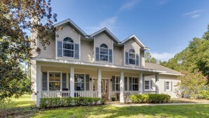 A two-story house with a porch, multiple windows, and a well-maintained lawn. - Pool, Patio + Game Room! Secluded Montverde Home (Montverde)