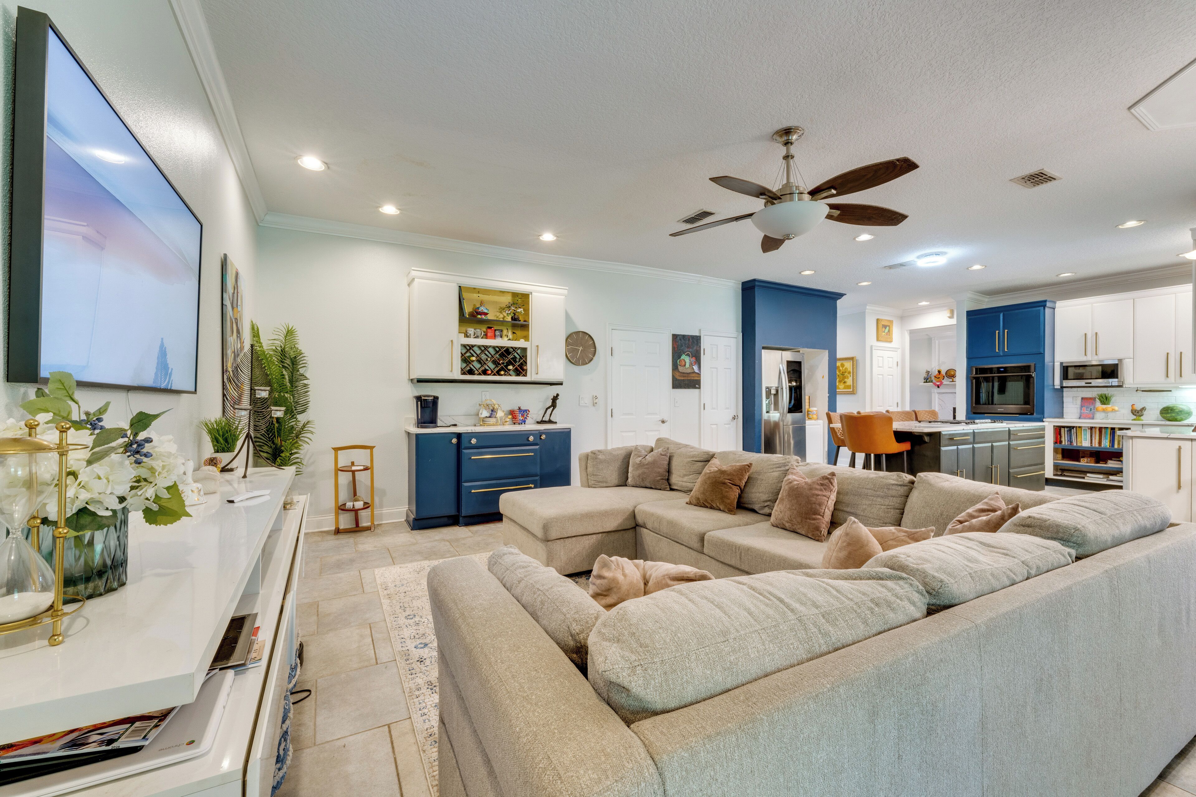 A modern living room with a sectional sofa, a flat-screen TV, and a dining area with a table and chairs.