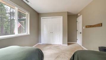A bedroom with two beds, a large window, and a door leading to another room.