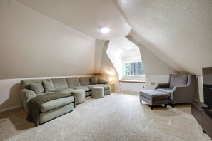 Ein Loft-Zimmer mit Ecksofa, Hocker, einem kleinen Tisch und einem Fernseher.