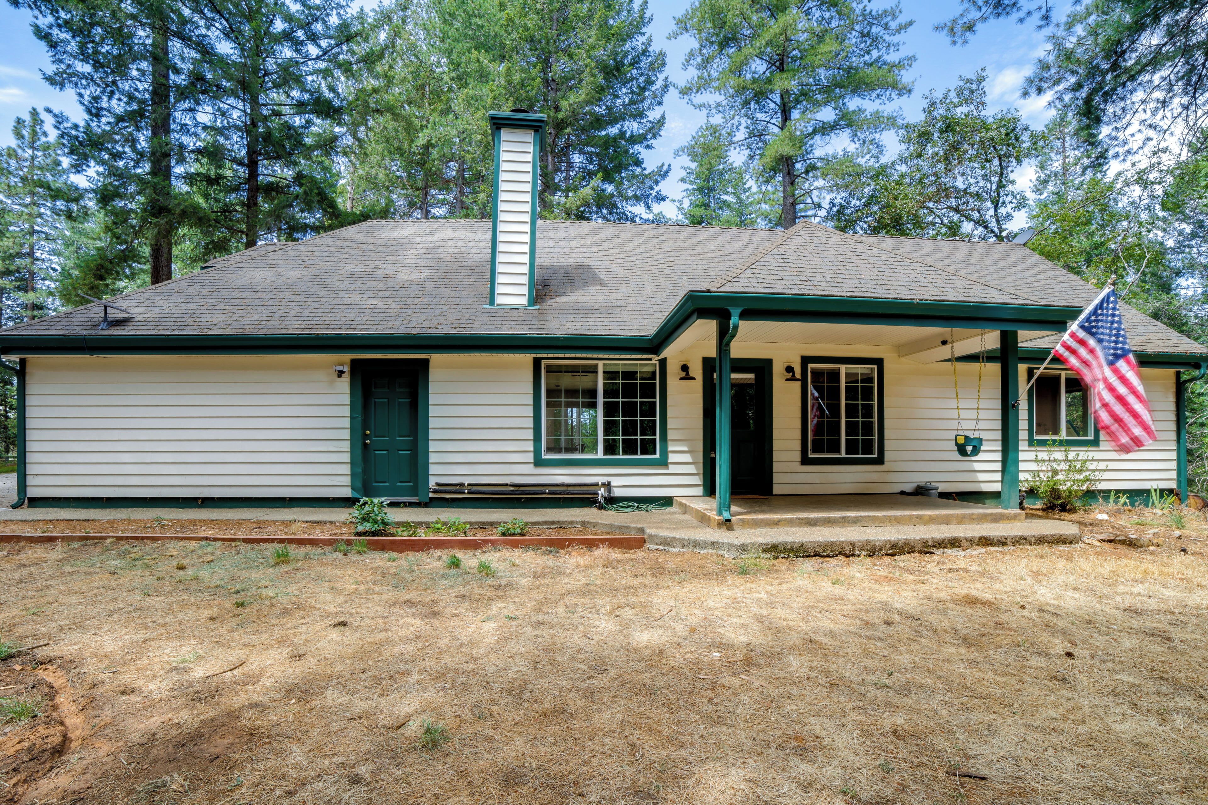 A single-story house with a gabled roof, a front porch, and a flag.