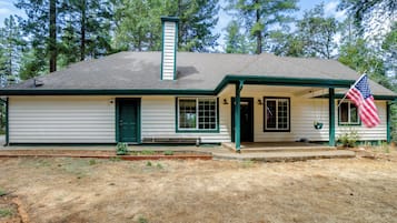 A single-story house with a gabled roof, a front porch, and a flag.