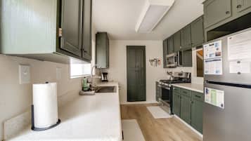 A modern kitchen with green cabinets, stainless steel appliances, and a white countertop.