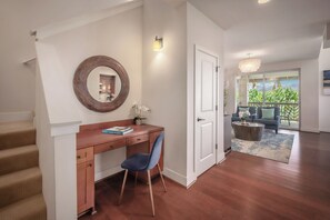 Un intérieur de maison avec un bureau en bois, une chaise et un miroir rond accroché au mur.