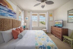 Une chambre à coucher comprenant un lit, un téléviseur, un ventilateur de plafond et une fenêtre donnant sur l’extérieur.