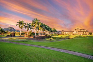 Un parcours de golf doté d’un club-house, de palmiers et offrant une vue sur un paysage montagneux.