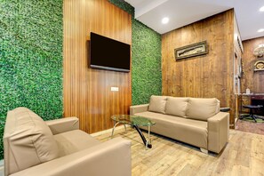 A modern interior with a sofa, a glass table, and a wall-mounted TV. - Palette Mundra Formerly (Mundra)