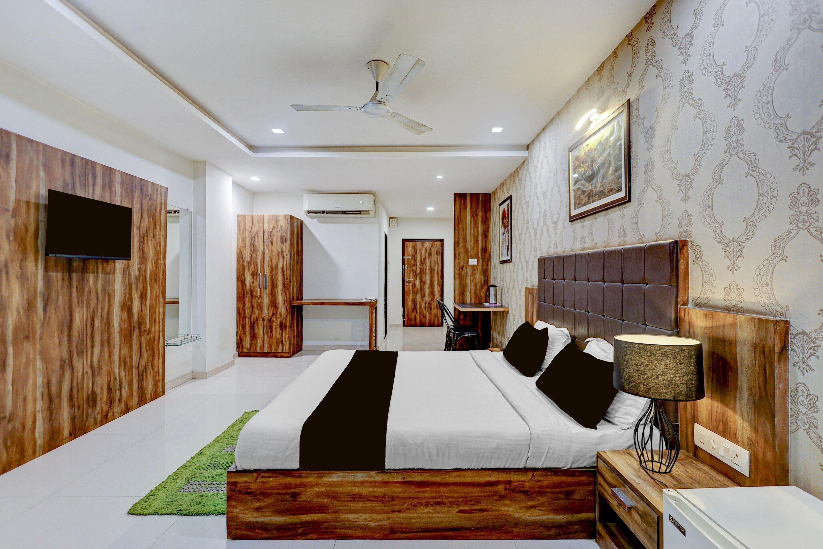 A modern bedroom with a bed, bedside table, lamp, and a ceiling fan.