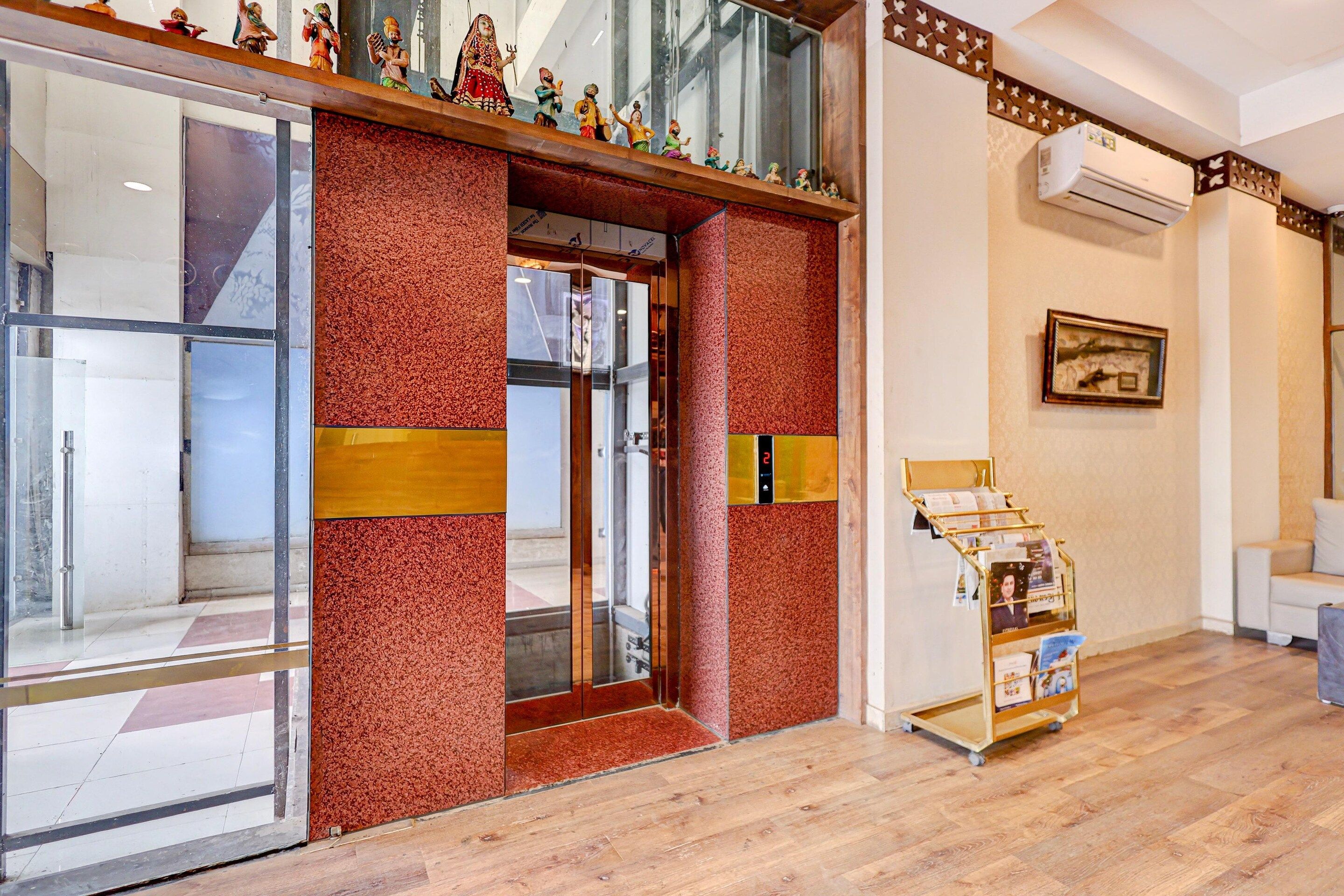 A hotel entrance with a red textured wall, a glass door, and a digital display showing the number 2.