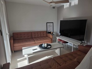 Uma sala de estar moderna com um sofá, uma mesa de centro, uma televisão e um quadro na parede.