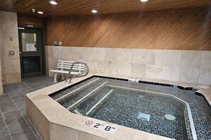 A hot tub with a tiled floor and a wooden wall. There is a bench and a door in the background. - King Bed Studio, Free Shuttle to Slopes & Main Street - Moose Mgmt 425 (Park City)