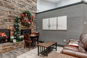A cozy living room with a stone fireplace, a Christmas tree, and a chessboard. - King Bed Studio, Free Shuttle to Slopes & Main Street - Moose Mgmt 425 (Park City)