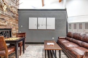A room with a fireplace, a chess table, a leather couch, and a wall with lockers. - King Bed Studio, Free Shuttle to Slopes & Main Street - Moose Mgmt 425 (Park City)
