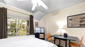 A hotel room with a bed, a desk, a chair, a ceiling fan, a window with curtains, and a framed picture on the wall. - King Bed Studio, Free Shuttle to Slopes & Main Street - Moose Mgmt 425 (Park City)