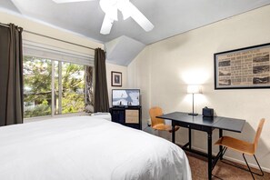 A hotel room with a bed, a desk, a chair, a ceiling fan, a window with curtains, and a framed picture on the wall. - King Bed Studio, Free Shuttle to Slopes & Main Street - Moose Mgmt 425 (Park City)