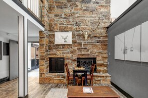 A stone fireplace with a deer skull and antlers decoration, a chessboard, and a table with magazines. - King Bed Studio, Free Shuttle to Slopes & Main Street - Moose Mgmt 425 (Park City)