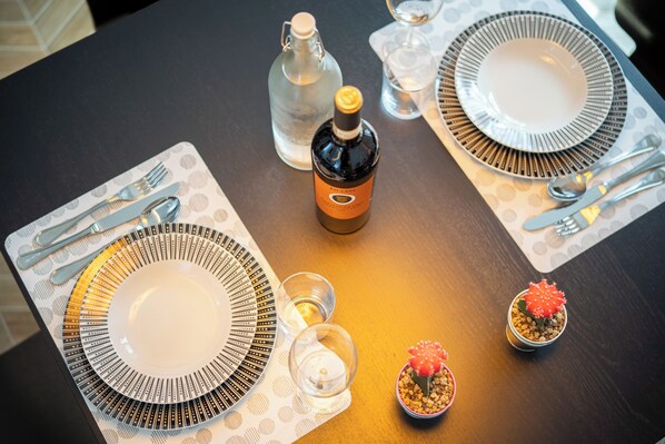 A table set with plates, cutlery, a bottle, glasses, and a small cactus plant. - Perseus Apartment near the Colosseum – A stylish stay in the heart of Rome (Roma)