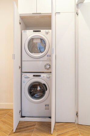 A compact laundry room with two stacked front-loading washing machines. - Perseus Apartment near the Colosseum – A stylish stay in the heart of Rome (Roma)