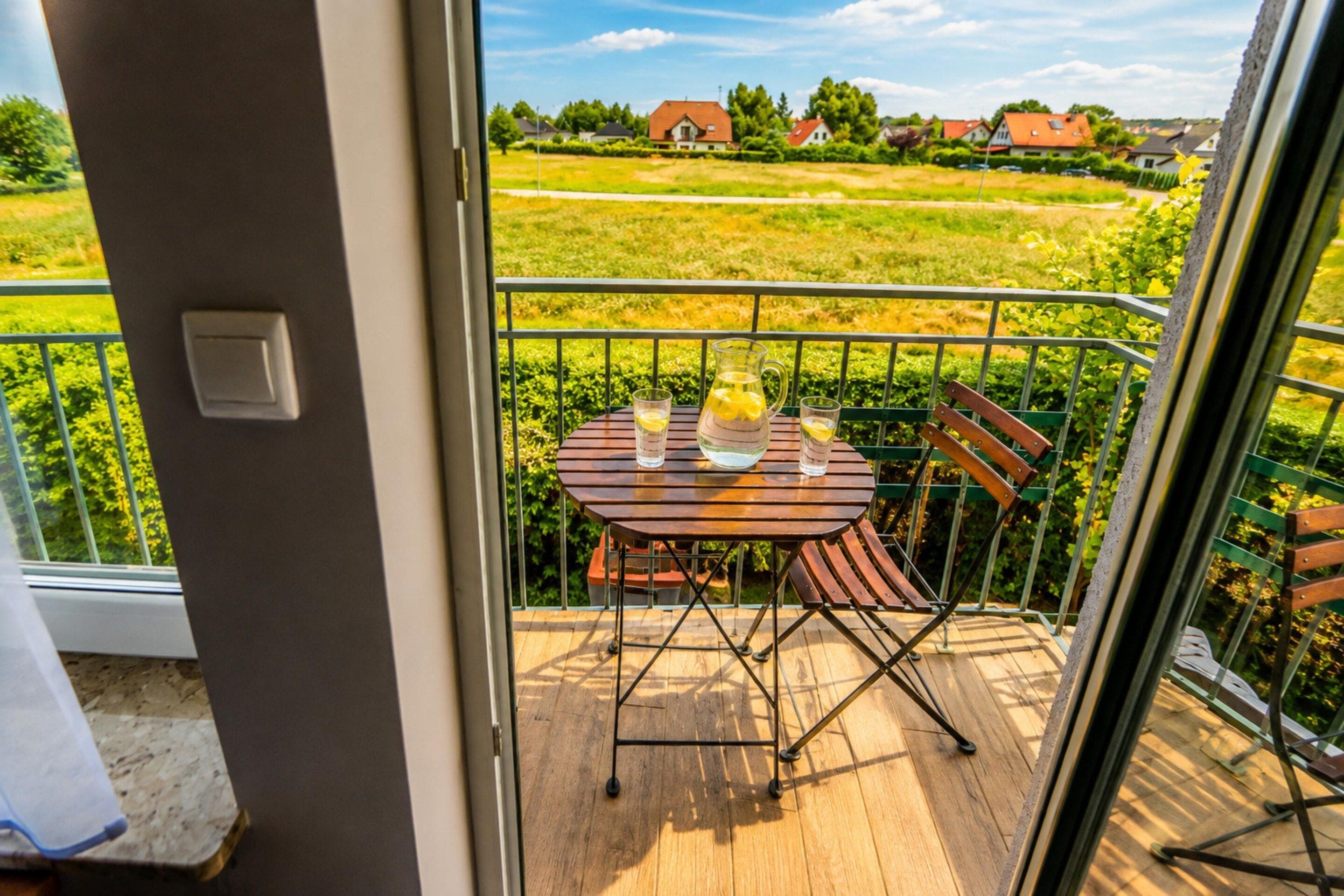 A balcony with a table and chairs, a pitcher of water, and a glass of water.