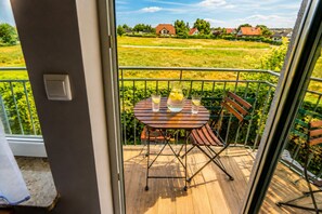 Un balcon avec une table et des chaises, une carafe d’eau et un verre d’eau.