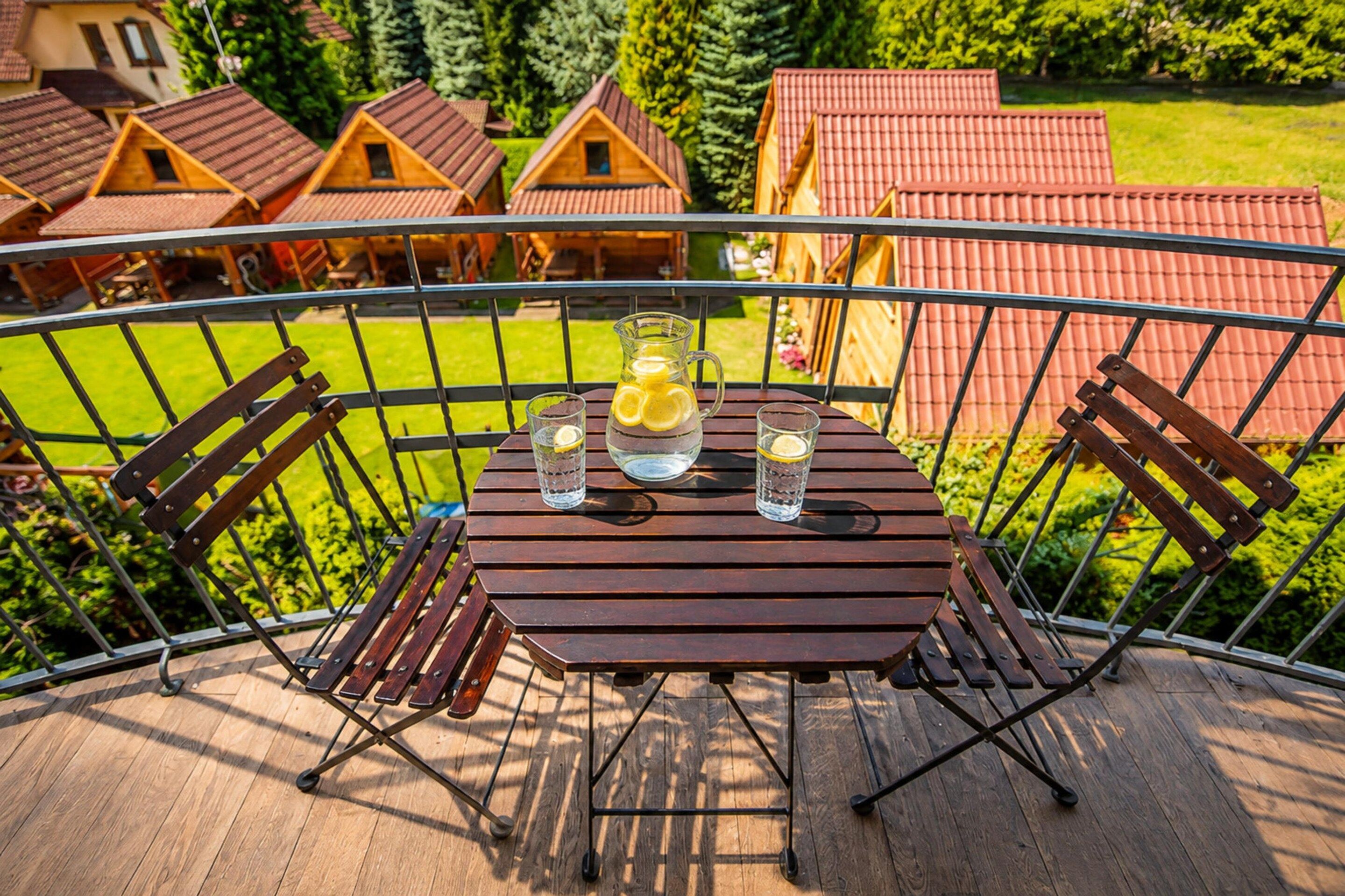 A balcony with a table set for two, a pitcher, and glasses.