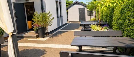 An outdoor patio area with a seating arrangement, a small building, and potted plants.