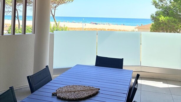 A covered patio with a table and chairs, overlooking a beach. - Unique in St Cyprien, right on the water (Saint-Cyprien)
