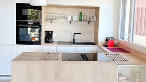 A modern kitchen with a central island, a built-in oven, and a coffee machine. - Unique in St Cyprien, right on the water (Saint-Cyprien)