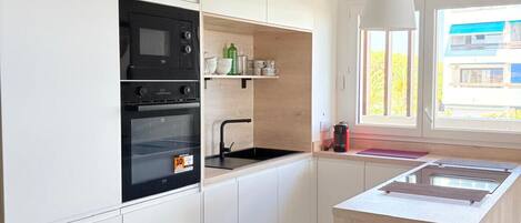A modern kitchen with white cabinets, a black oven, and a wooden island with a sink.