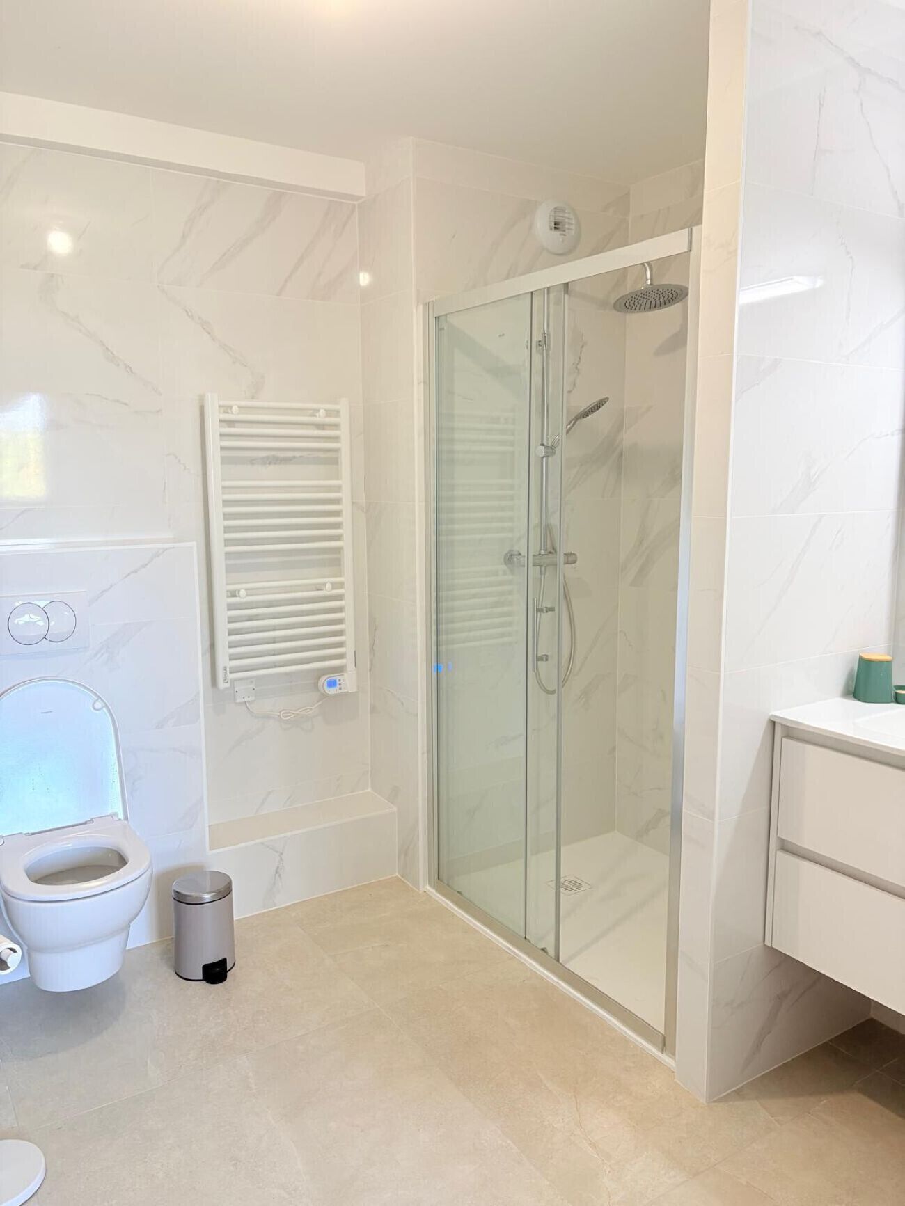 Een moderne badkamer met een douchecabine van glas, een toilet en een wastafel.