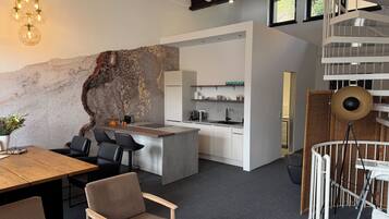 Eine moderne Küche mit weißen Schränken, einer zentralen Kochinsel und einem Essbereich mit Holztisch und Stühlen.