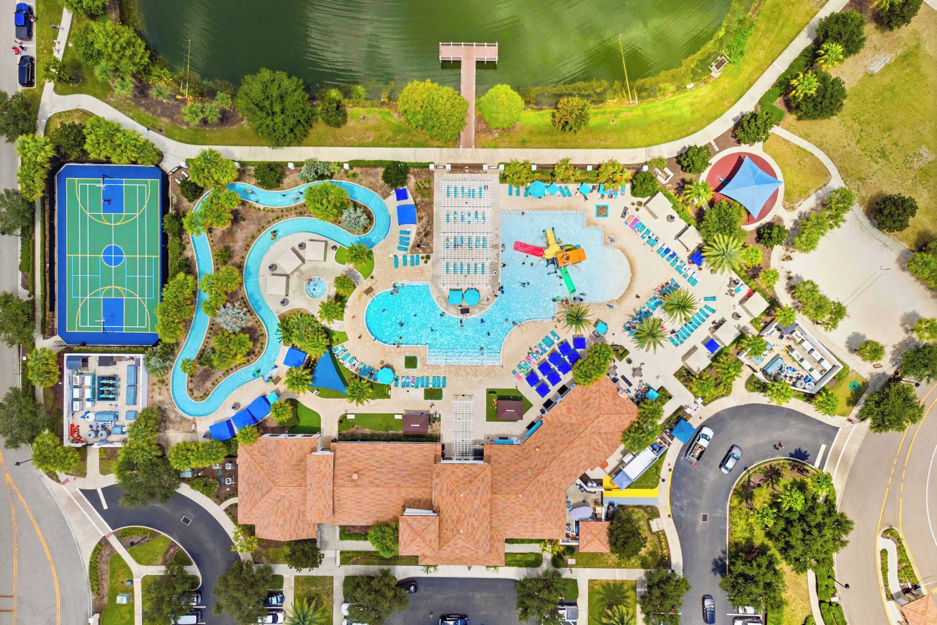 Vista aérea de un resort con una amplia piscina, cancha de baloncesto y cancha de tenis.