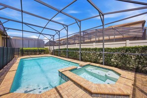 A swimming pool with a hot tub, surrounded by a metal fence and a hedge. - Windsor Paradise | 8BR Resort Villa Near Disney (Kissimmee)
