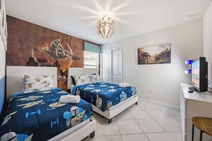 Ein Hotelzimmer mit zwei Betten, einem großen Wandbild, einem Schreibtisch mit Computer und einem Fernseher.