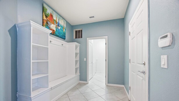 A hallway with white built-in shelving, a door at the end, and a painting above.