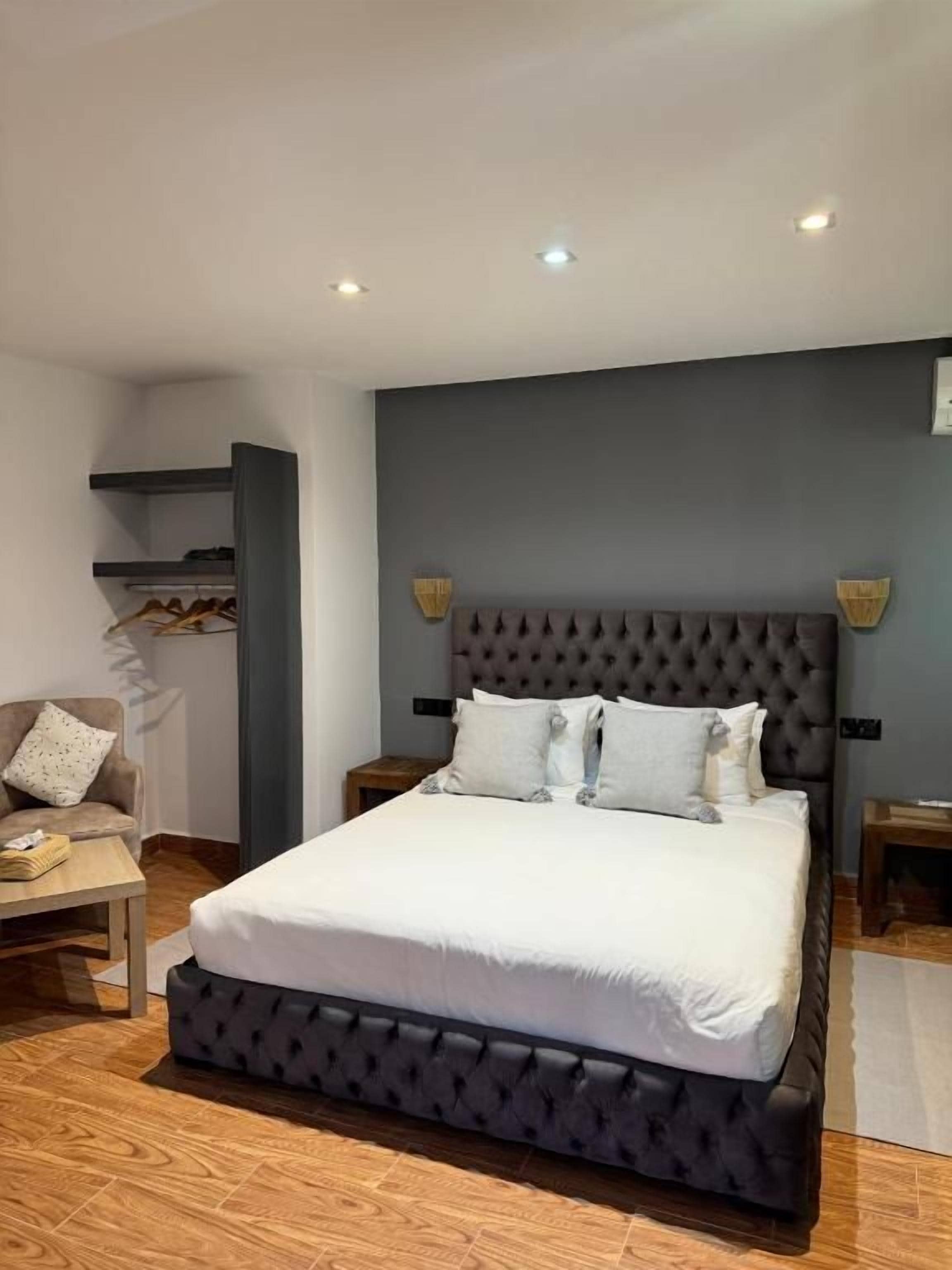Une chambre moderne avec un grand lit, une armoire intégrée et un coin salon avec une table.