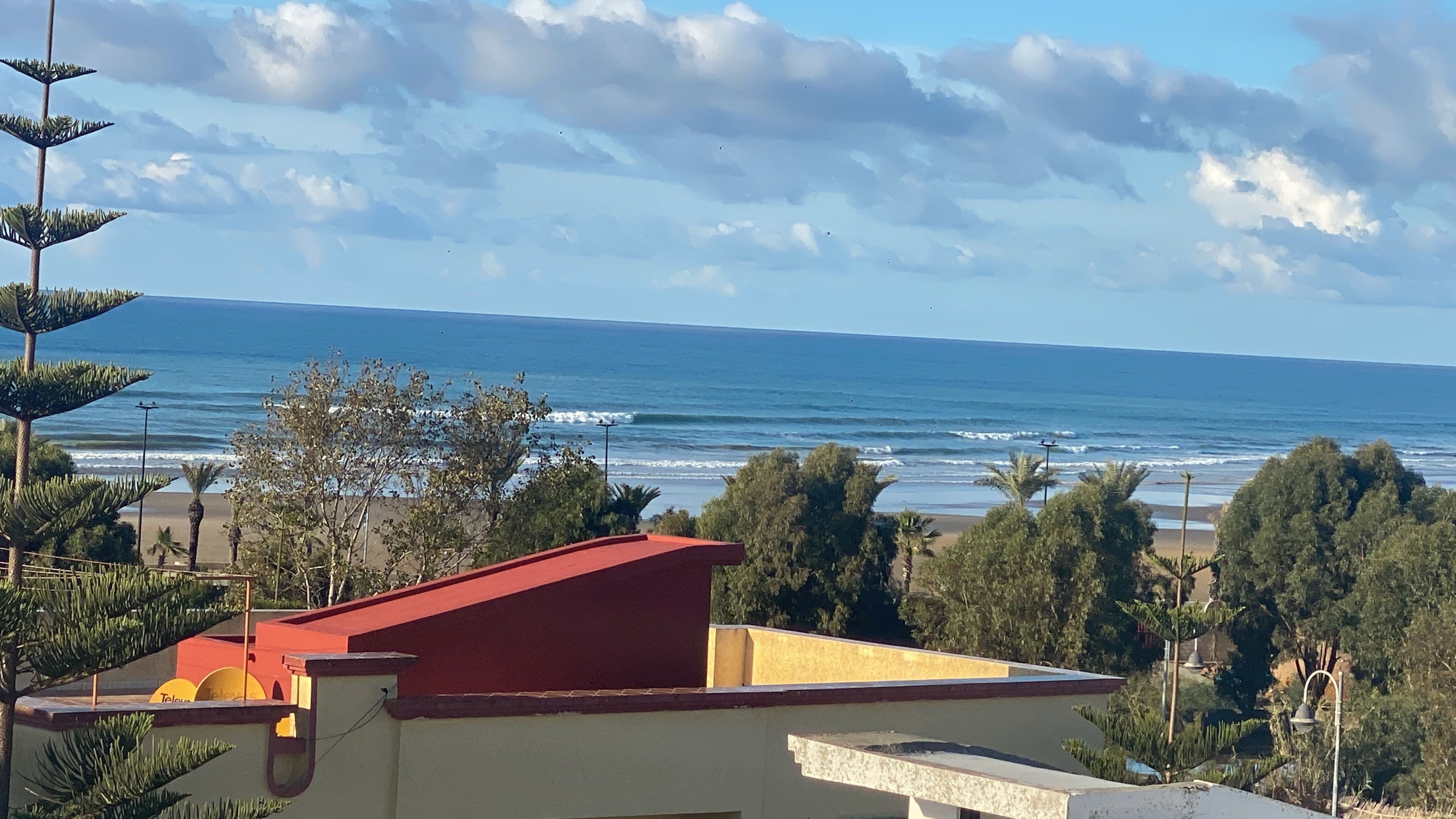 Vista costera con un edificio en primer plano, una playa y el océano.