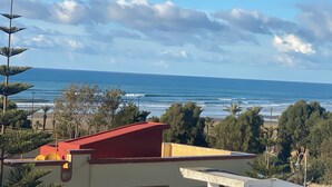 A coastal view with a building in the foreground, a beach, and the ocean.