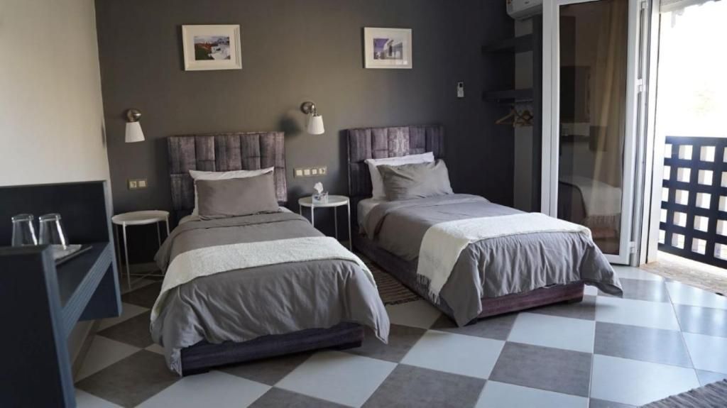 Une chambre d’hôtel avec deux lits, une petite table, une chaise et une vue sur l’extérieur.