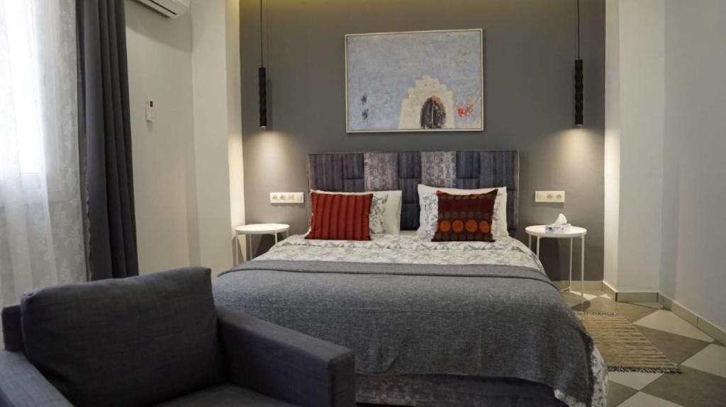 A bedroom with a bed, two bedside tables, a chair, and a painting on the wall.