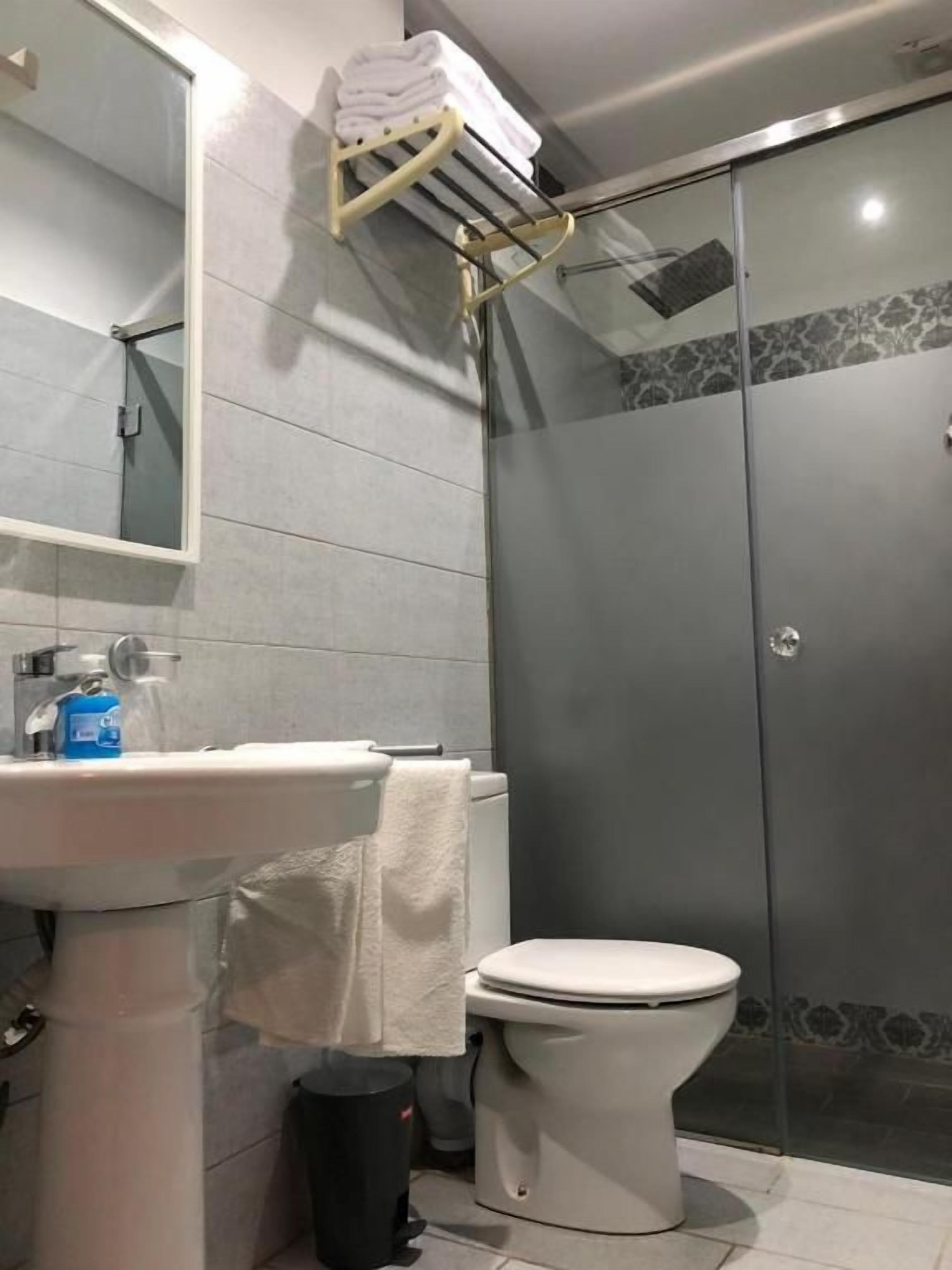Une salle de bain avec un lavabo blanc, des toilettes et une douche séparée par une paroi de verre.