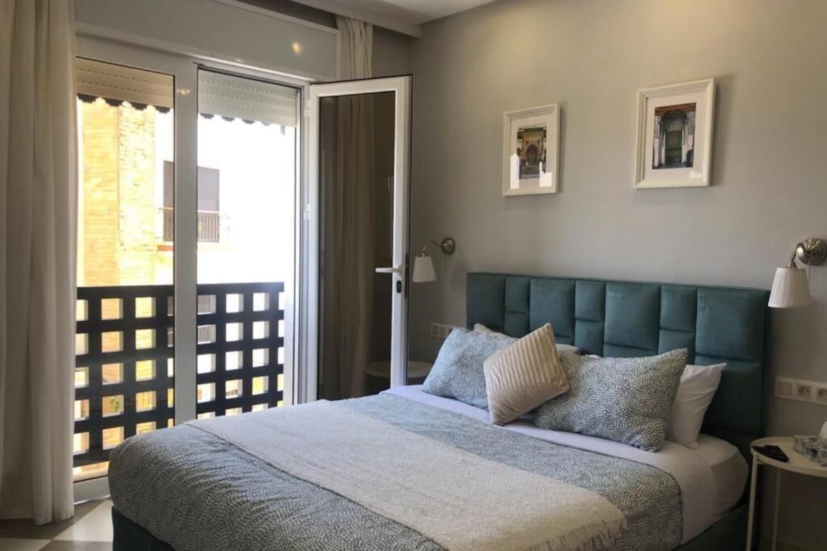 A bedroom with a bed, a nightstand, a lamp, and a view through a sliding door.