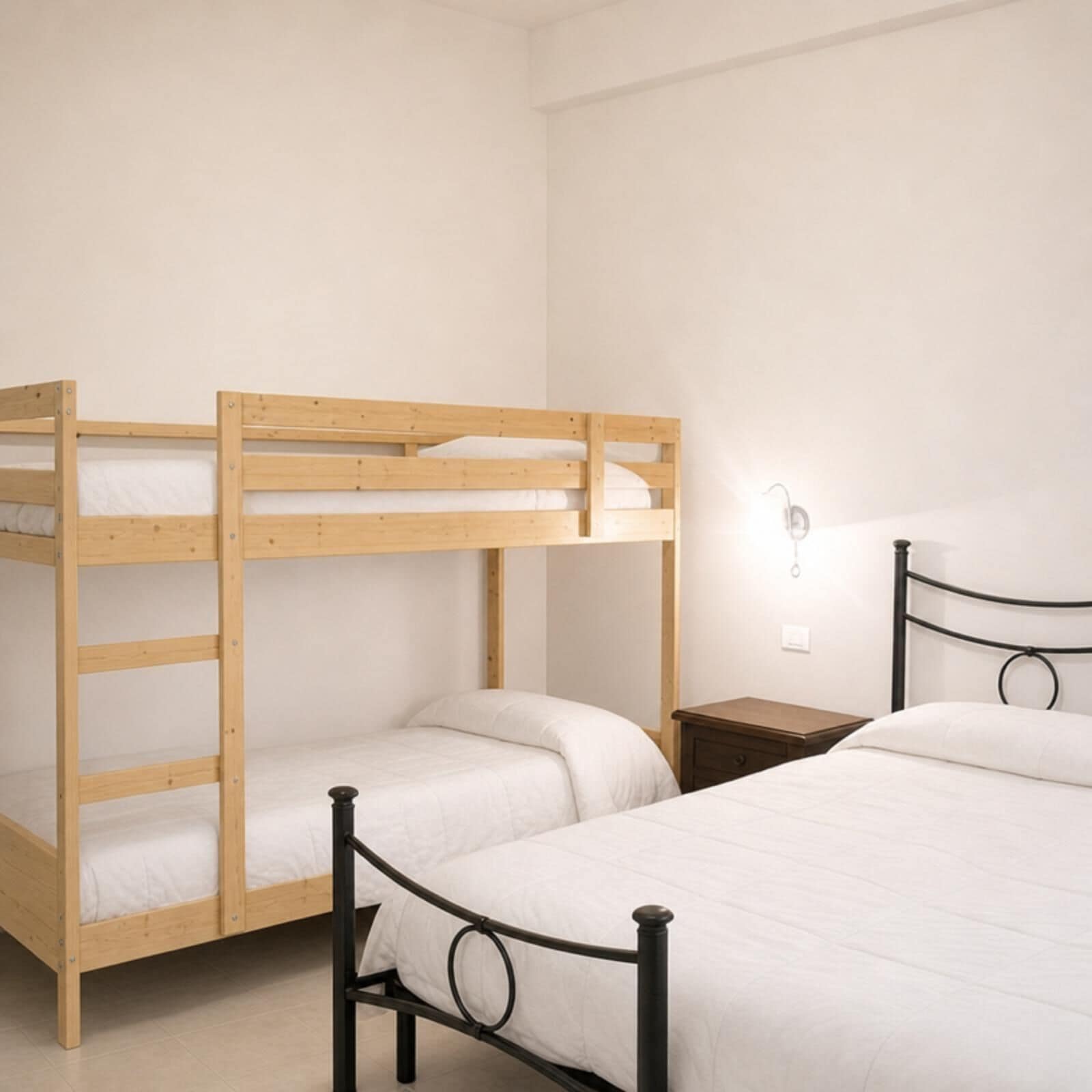 Un letto a castello con struttura in legno e un letto inferiore con struttura metallica.